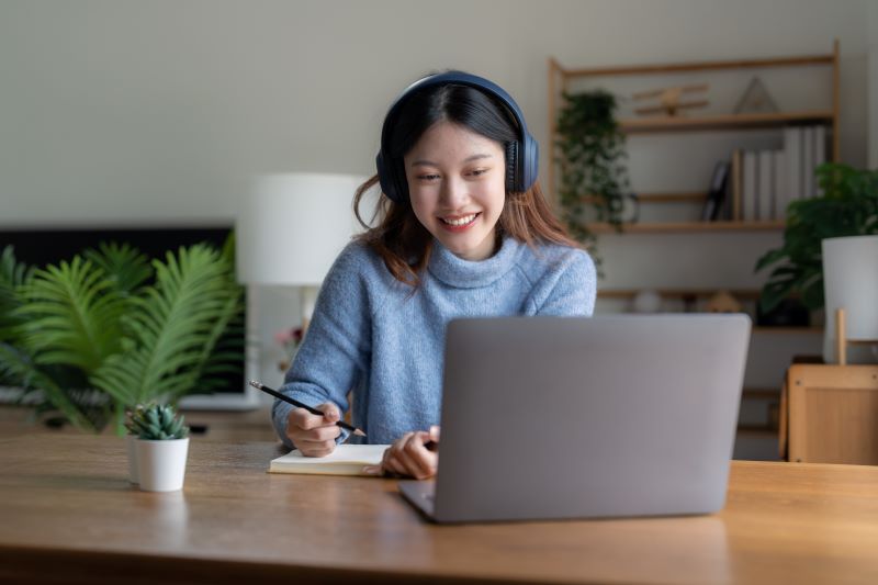 smiling-girl-student-wear-headphone-study-online-with-teacher-happy-young-asian-woman-learn-language-listen-lecture-watch-webinar-write-notes-look-laptop-sit-cafe-distant-education.jpg